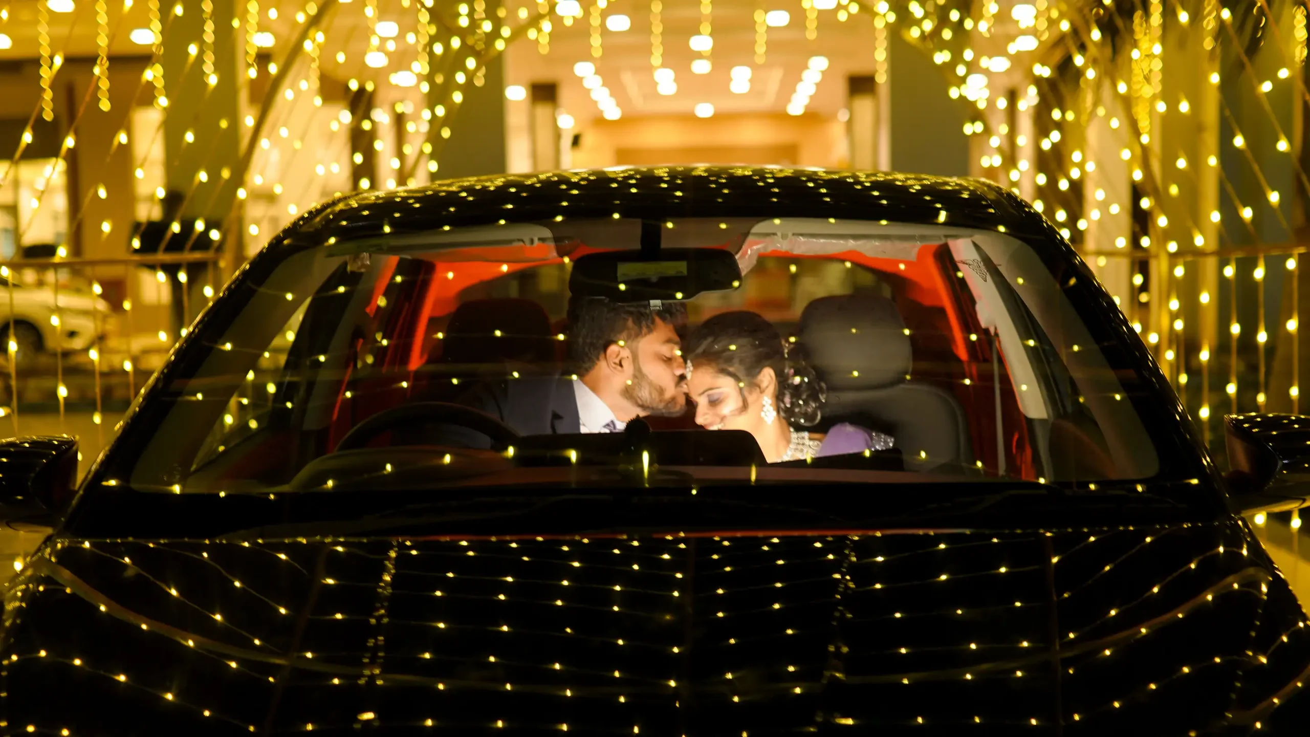 Bride and groom sharing a tender forehead kiss in a decorated car at night by Yuvi Studio 🏢 Yuvi Studio Fotography & Film Making 📷 Best Outdoor Wedding PhotoShoot 📍 Velayuthampalayam, Karur